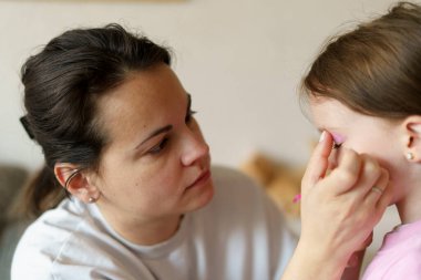 Anne küçük kızına makyaj yapıyor. Sağlıklı aile ilişkileri kavramı