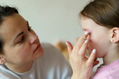 Anne küçük kızına makyaj yapıyor. Sağlıklı aile ilişkileri kavramı