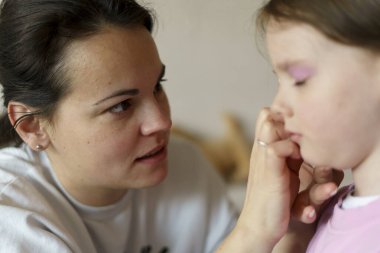 Anne küçük kızına makyaj yapıyor. Sağlıklı aile ilişkileri kavramı