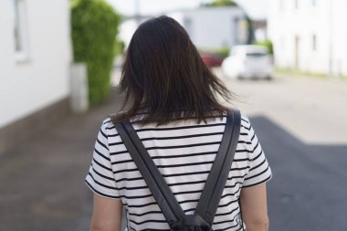 Yazın dışarıda, kaldırımda sırt çantasıyla yürüyen bir kızın fotoğrafı. Sağlıklı aktif seyahat kavramı