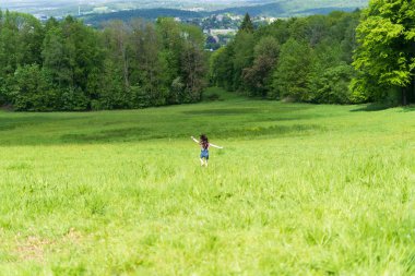 Küçük kız büyük yeşil bir yaz tarlasında mutlu bir şekilde koşuyor. Aktif sağlıklı çocuk kavramı