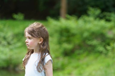 Küçük tatlı üzgün kız yaz parkında yürüyor. Dışarıdaki üzgün çocuk kavramı