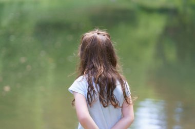 Little cute sad girl walking in summer park. Concept of sad child outdoors clipart