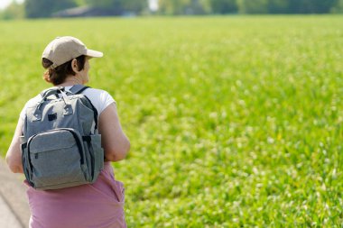 Sırt çantalı bir kadın tarlada dikiz aynasından görülüyor. Etkin seyahat konsepti