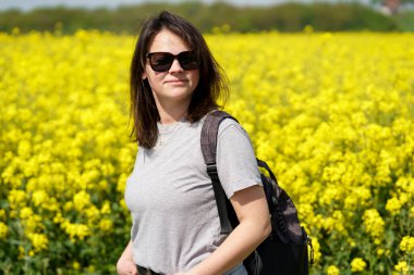Kolza tarlasında genç bir kadın. Seçici bir şekilde kadına odaklan. Etkin seyahat konsepti