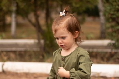 Yeşil elbiseli neşeli aktif anaokulu kızı yazın dışarıda oynuyor. Çocukların eğlence ve eğlence anlayışı