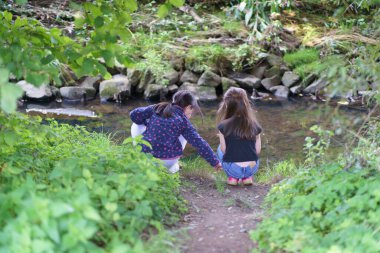 Yaz ormanında bir derenin kenarında oturan iki küçük kız. Çocuk arkadaşlığı kavramı
