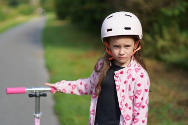Yaz parkında asfalt yolda scooterlı küçük kız. Etkin çocuk kavramı