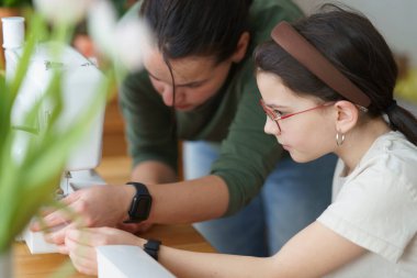 Bir anne kızına dikiş makinesinin ipliğini nasıl bağlayacağını ve dikiş dikeceğini gösterir. Eğitici ve yaratıcı çocuk konsepti.