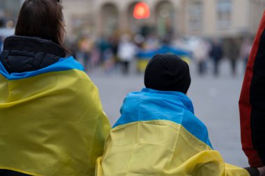 Ukrayna 'yı destekleyen bir mitingde omuzlarında Ukrayna bayraklarıyla tanınmayan insanlar arkadan fotoğraflandı.