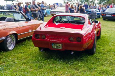 Iserlohn Gruermannscheide, NRW, Almanya. 13 Temmuz 2024. Kırmızı Targa Chevrolet Corvette C3 yazın bir araba fuarında, arka planda..