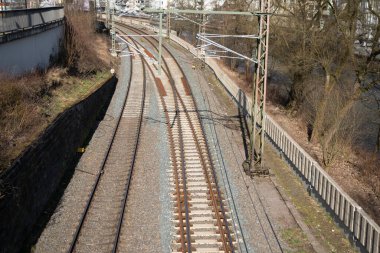 Taştan bir duvarın yanında elektrik hatları olan yakın plan bir tren yolu. Demiryolu taşımacılığı kavramı