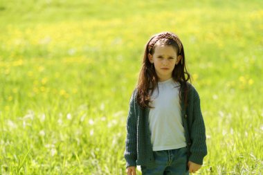 Kazaklı, kot pantolonlu, gücenmiş küçük bir kız bir tarlanın ortasında duruyor. Çocukluğun zorlukları kavramı.