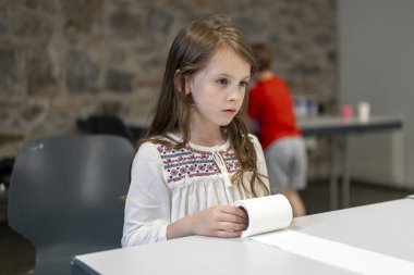 Okul kantininde güzel işlemeli gömlekli bir kız aktif masa oyunları oynuyor. Çocukların aktivitesi ve oyunu hakkında eğitici bir kavram.