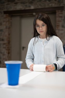 Gözlüklü ve kazaklı bir kız okul kafeteryasında oyun oynuyor. Çocukların aktivitesi ve oyunu hakkında eğitici bir kavram.