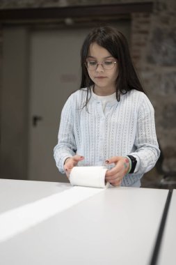 Gözlüklü ve kazaklı bir kız okul kafeteryasında oyun oynuyor. Çocukların aktivitesi ve oyunu hakkında eğitici bir kavram.