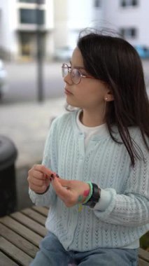 Gözlük takan ve sweatshirt giyen bir kız dışarıda titiz bir sanat çalışması yapıyor. Çocukların yaratıcılığı kavramı