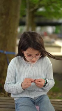 Gözlük takan ve sweatshirt giyen bir kız dışarıda titiz bir sanat çalışması yapıyor. Çocukların yaratıcılığı kavramı