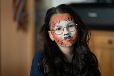 Hayvan suratlı ve gözlüklü 10 yaşında bir kız. Ciddi bir ifadeyle içeride oturuyor. Kavram: çocukluk duyguları, tefekkür, derinlik, masumiyet, sessiz anlar