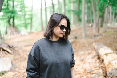 Düşen ağaçlar ve kuru yapraklar arasında bir kadın figürü. Kavram: dünyevi tonlar, iç huzur, orman geri çekilmesi, zamansız doğa bağı