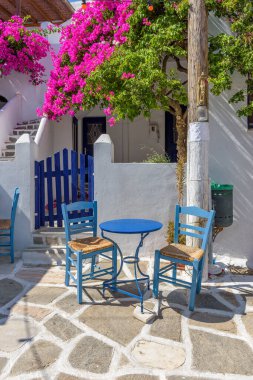 Traditional alley with whitewashed houses,an exterior of a greek tavern  and a  bougainvillea in Prodromos Paros island clipart