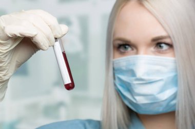 young woman wearing a medical face mask and medical gloves is handling a blood probe in a laboratory  clipart