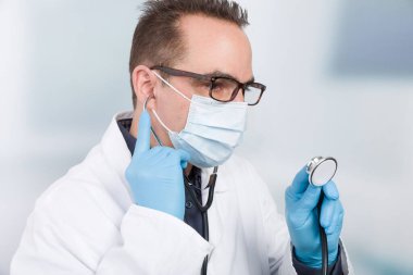 Steteskopla kliniğin önünde duran erkek doktor.