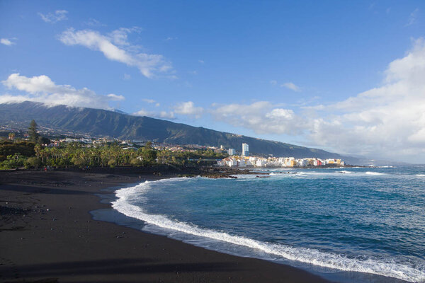 Tenerife town of Puerto de la Cruz with mountains, black sand beach and sea