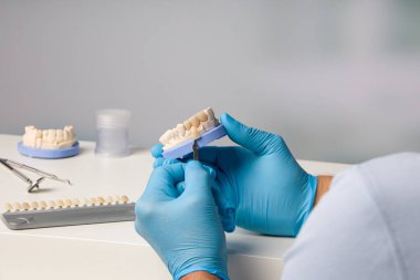 Diş laboratuarında diş kaplaması üzerinde çalışan diş teknisyenini kapatın.