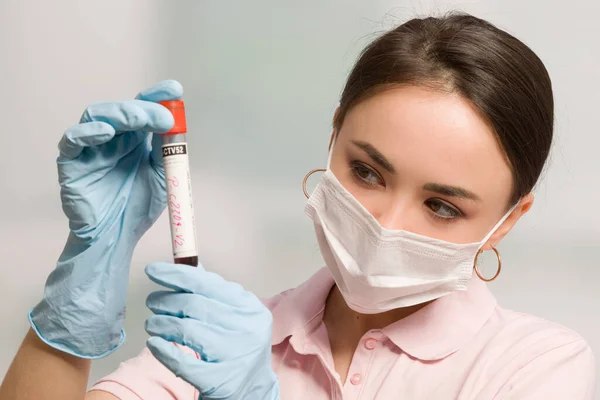 女性科学者や看護師が医療用手袋や医療用フェイスマスクを装着して研究室で血液検査を行っています — ストック写真