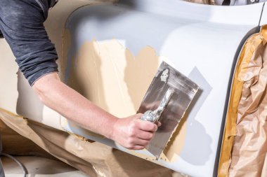 Klasik bir arabanın ön yüzeyi üzerinde spatulayla çalışmanın yakın çekimi.