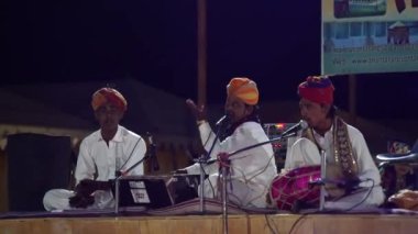 Sanatçı bir Rajasthani halk şarkısı söylüyor, Thar Çölü 'nde Sam Dunes adında bir kampta kültür programı. Jaisalmer, Rajasthan, Hindistan - Kasım 2022