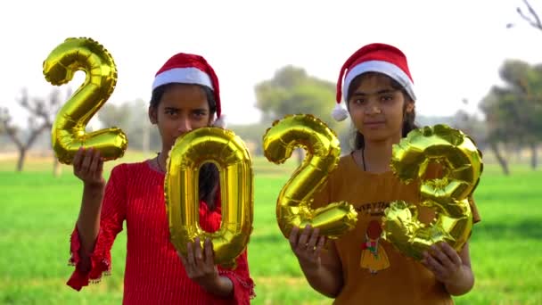 庭で大晦日を祝う幸せな子供たち 次の新年を表す輝きとイルミネーション番号2023を保持 — ストック動画