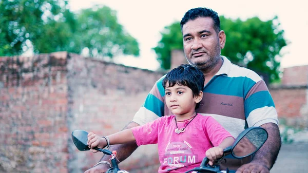 快乐的农村印度父亲和孩子骑摩托车 蹒跚学步的孩子坐在摩托车上 而爸爸把他抱在摩托车上 Sikar Rajasthan India Nov 2022 — 图库照片