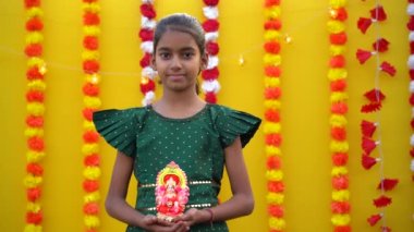 Sevimli Hintli küçük kız elinde Lord Ganesha Sclupture 'u tutuyor ve Diwali festivalini kutluyor..
