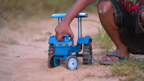 フィールド上のおもちゃのトラクターで遊んで小さな男の子 地面に座っておもちゃトラクターや砂で遊ぶかわいい幼児の少年の肖像画 子供は屋外で歩く ライフスタイル — ストック動画