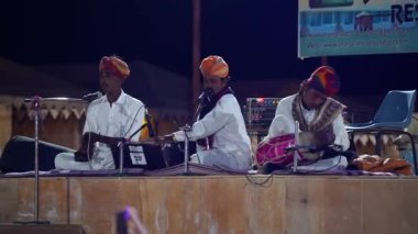 Sanatçı bir Rajasthani halk şarkısı söylüyor, Thar Çölü 'nde Sam Dunes adında bir kampta kültür programı. Jaisalmer, Rajasthan, Hindistan - Kasım 2022
