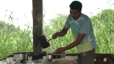 Dhaba 'da çay yapan bir adam. Fakir bir çaycı çayını küçük çay dükkanında yapar ve döker..