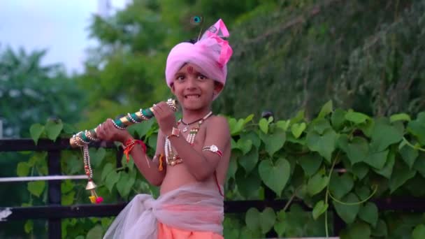 リトル クリシュナが走る クリシュナ ヤンマシュタミ公 クリシュナカンハの愛らしいインドの赤ん坊またはカニヤのドレスはフルートでポーズ — ストック動画