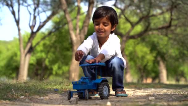 遊び場で彼のおもちゃのトラクターで遊んでかわいい幼児の少年の肖像画 プラスチック製のおもちゃの子供 ライフスタイル — ストック動画
