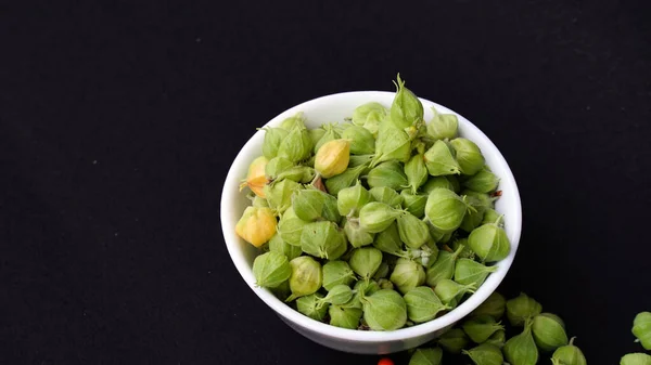 stock image Ashwagandha Dry Root Medicinal Herb with Fresh Leaves, also known as Withania Somnifera, Ashwagandha, Indian Ginseng, Poison Gooseberry, or Winter Cherry. Isolated on Dark Background.