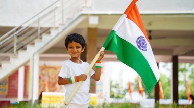 Elinde Kızılderili bayrağı tutan ve gülümseyen sevimli küçük çocuk. Hindistan 'da Bağımsızlık Günü veya Cumhuriyet Günü' nü kutluyoruz. Tiranga 'nın gururunu gösteren çocuk