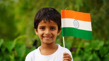 Elinde Kızılderili bayrağı tutan ve gülümseyen sevimli küçük çocuk. Hindistan 'da Bağımsızlık Günü veya Cumhuriyet Günü' nü kutluyoruz. Tiranga 'nın gururunu gösteren çocuk