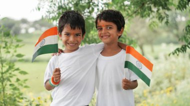 Ellerinde Kızılderili bayrağı tutan ve gülümseyen şirin çocuklar. Hindistan 'da Bağımsızlık Günü veya Cumhuriyet Günü' nü kutluyoruz. Tiranga 'nın gururunu gösteren çocuk