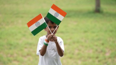 Elinde Kızılderili bayrağı tutan ve gülümseyen sevimli küçük çocuk. Hindistan 'da Bağımsızlık Günü veya Cumhuriyet Günü' nü kutluyoruz. Tiranga 'nın gururunu gösteren bir çocuk.