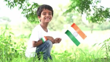 Ulusal gururunu göstermek için üç renkli Kızılderili bayrağıyla küçük şirin bir çocuğun portresi. Bağımsızlık Günü