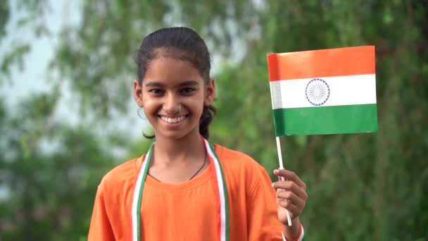 小さなインドの少女は インドのモデルである独立記念日または共和国の日を祝います カメラに向かって向かってトリコロールの旗で立っている魅力的な少女 — ストック動画