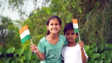 Hintli öğrenciler ya da çocuklar arka planda yeşillikle üç renkli el sallayarak Bağımsızlık ya da Cumhuriyet gününü kutluyorlar.