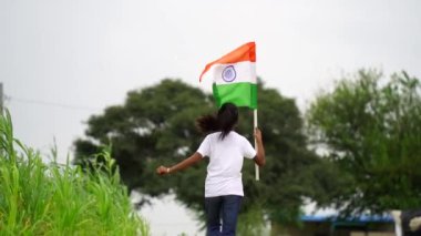 Sevimli küçük Hintli çocuklar el sallıyor ya da arka planda yeşillik ile koşuyorlar Bağımsızlık Günü 'nü ya da Cumhuriyet Günü' nü kutluyorlar.