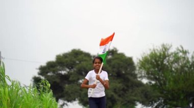 Sevimli küçük Hintli çocuklar el sallıyor ya da arka planda yeşillik ile koşuyorlar Bağımsızlık Günü 'nü ya da Cumhuriyet Günü' nü kutluyorlar.